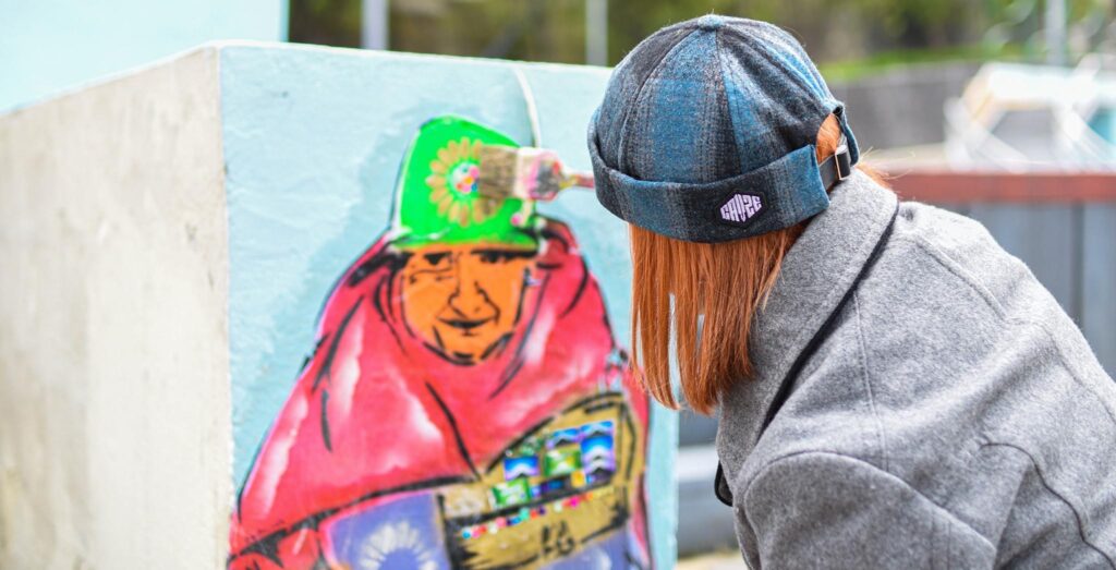 Artista callejera pintando una imagen de una mujer indígena mayor