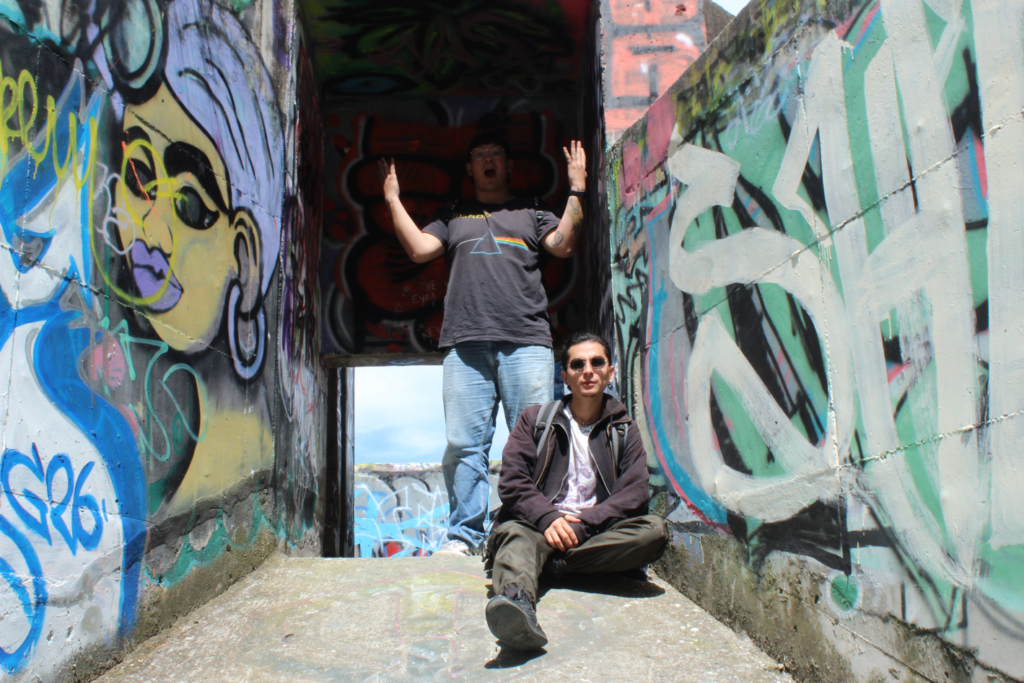 dos jovenes posando en un lugar abandonado lleno de graffitis